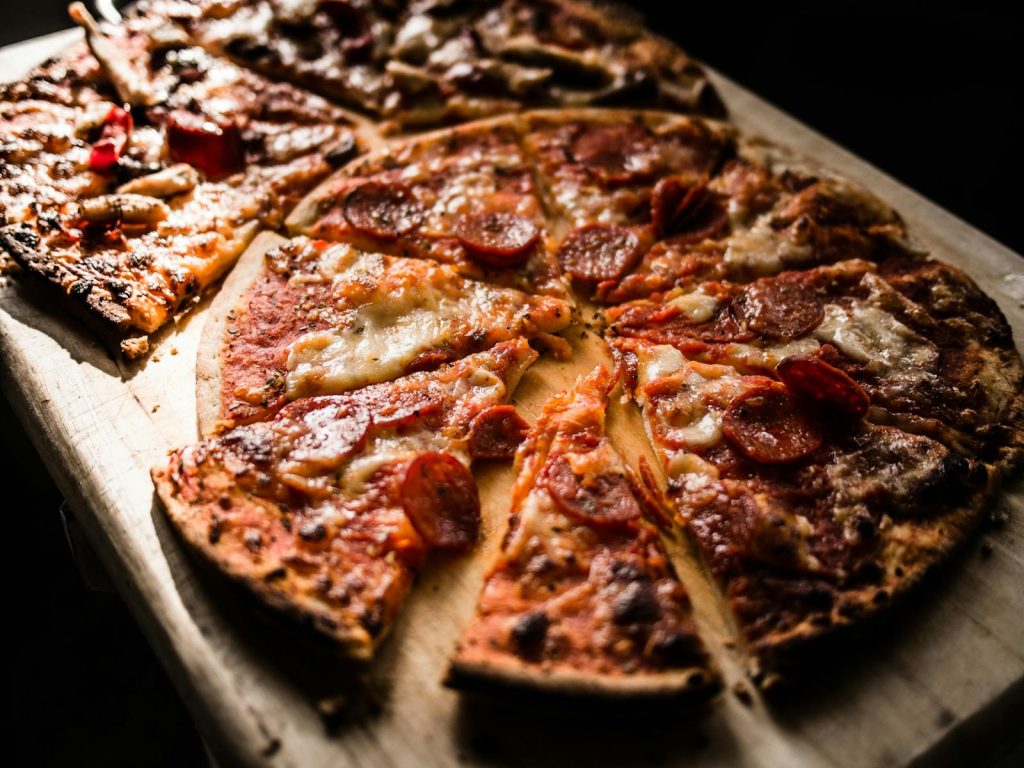 Delicious crispy pepperoni pizza slices on a wooden board, perfect for pizza lovers.