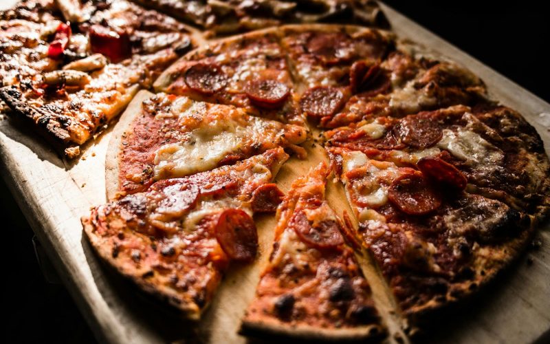 Delicious crispy pepperoni pizza slices on a wooden board, perfect for pizza lovers.